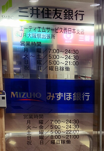 大阪駅のATMコーナー（2017年9月撮影）。三井住友銀行とみずほ銀行のATMの営業時間が表示されており、祝日についてはいずれも「曜日稼働」と記されている。